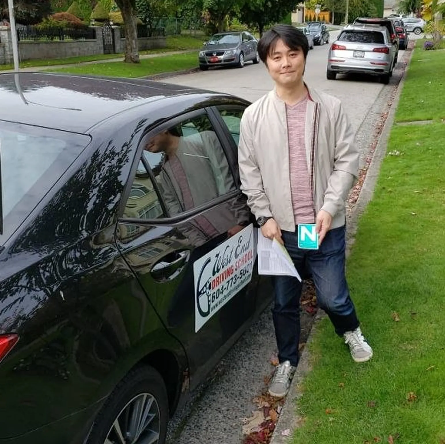 Learner holding N sign beside driving school vancouver vehicle