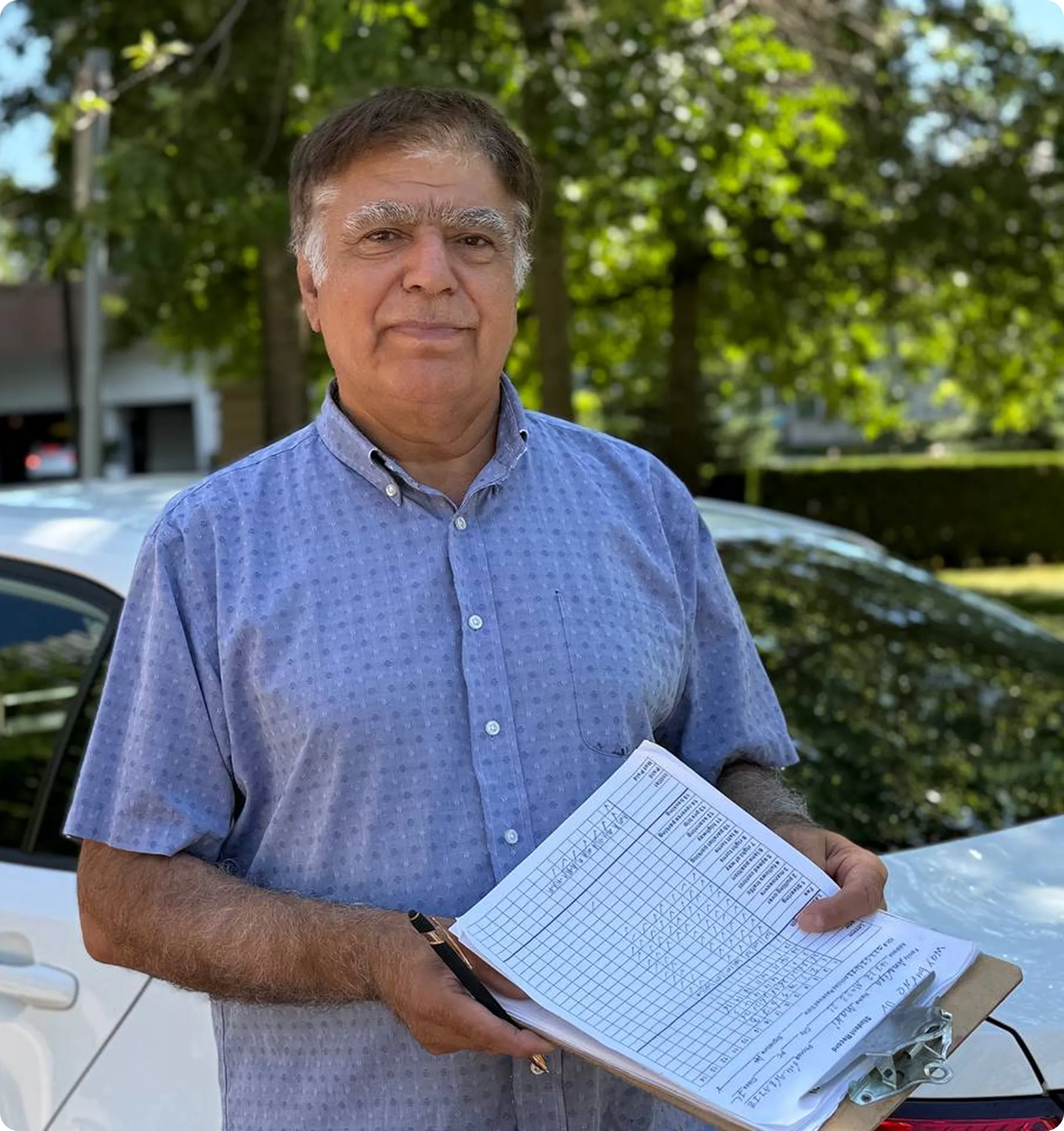 Mr. Vakili, founder of West End Driving School, holding lesson materials