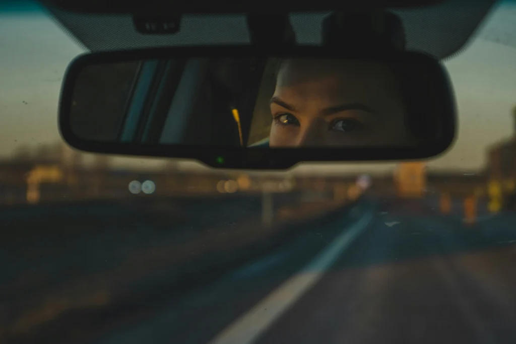 Driver checking mirrors while using defensive driving techniques
